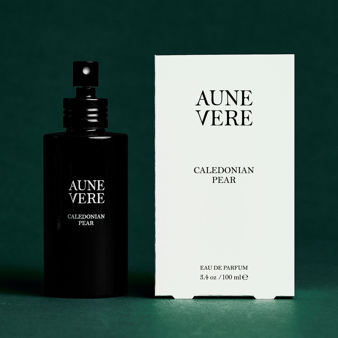 Caledonian Pear 100 ml bottle beside its carton, on green paper.