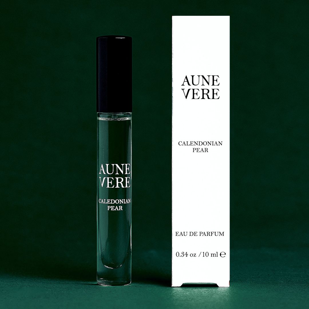 Caledonian Pear 10 ml bottle beside its carton, on green paper.